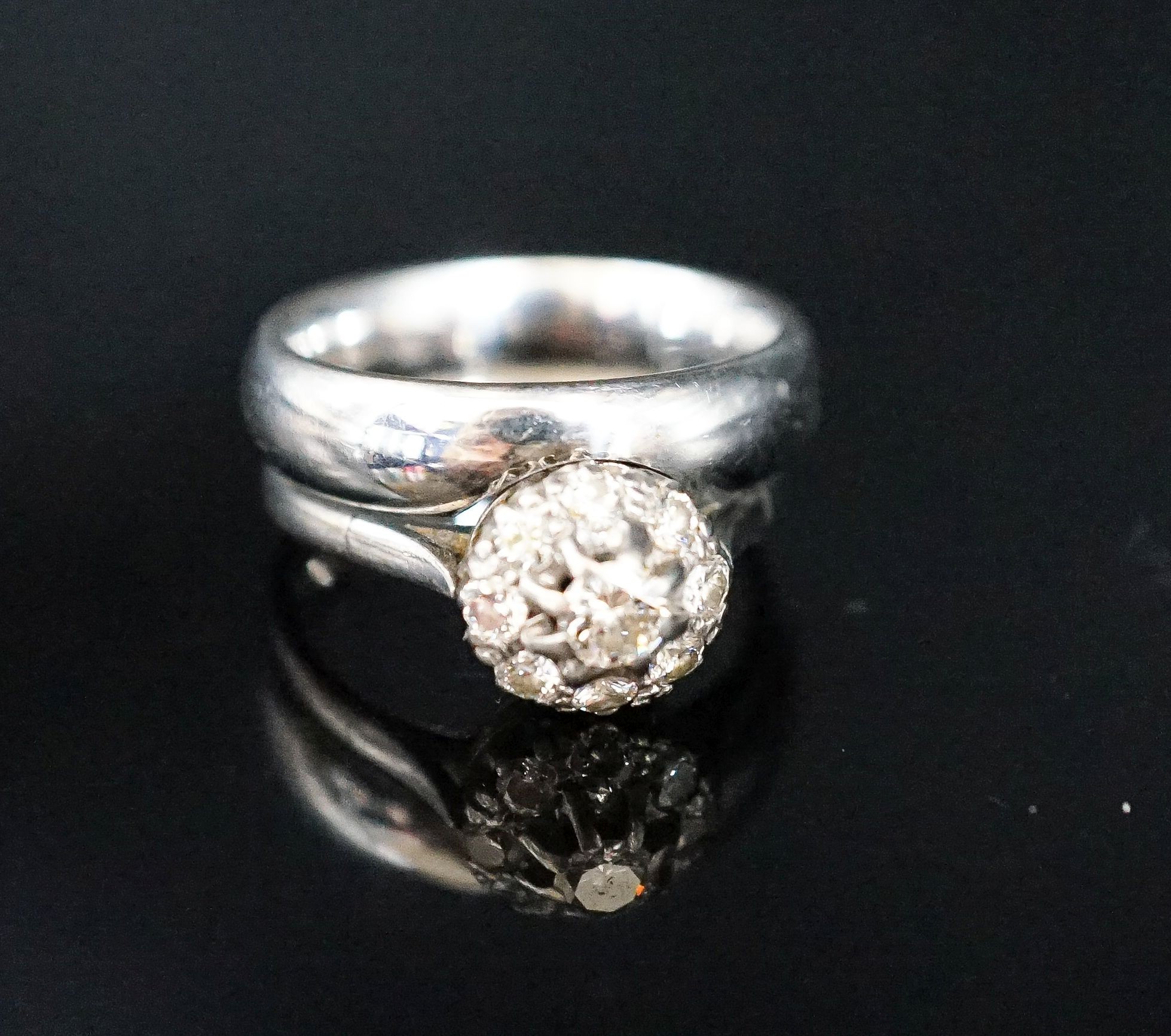 A modern 18ct white gold and diamond cluster ring, now soldered together with an 18ct white metal band, size P, gross weight 12.9 grams.